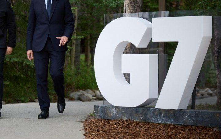 A three-dimensional white G7 sign along an outdoor path