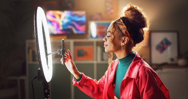 A woman sets up her smartphone on a ring light to record a video or take photos for social media content creation